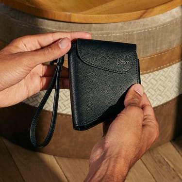 Χέρι που κρατά μια θήκη μεταφοράς Ploom Duo σε χρώμα Jet Black